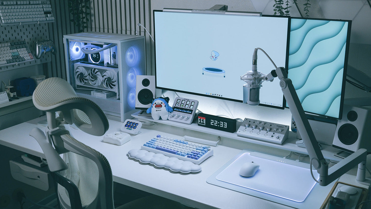 Minimalist white gaming desk setup featuring a custom mechanical keyboard, lightweight wireless mouse, dual monitors, and streaming microphone